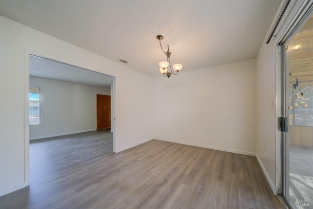 unfurnished room featuring a chandelier and hardwood / wood-style floors