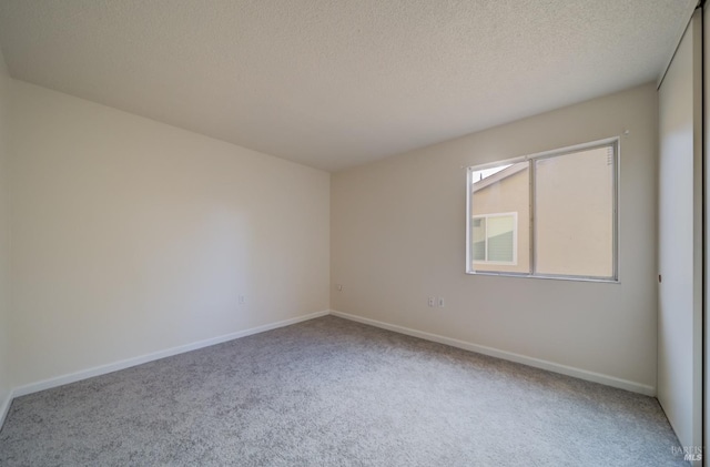 carpeted spare room featuring a textured ceiling