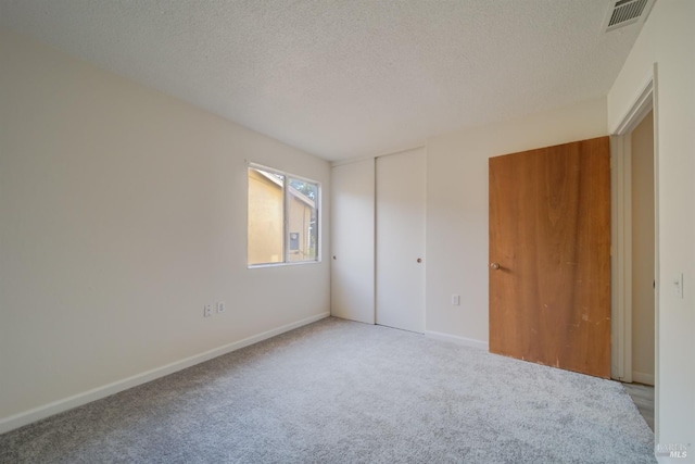 unfurnished bedroom with light colored carpet, a closet, and a textured ceiling