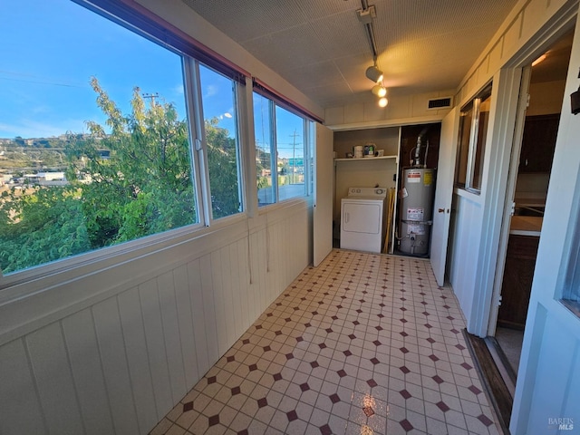 washroom featuring wooden walls, washer / clothes dryer, and water heater