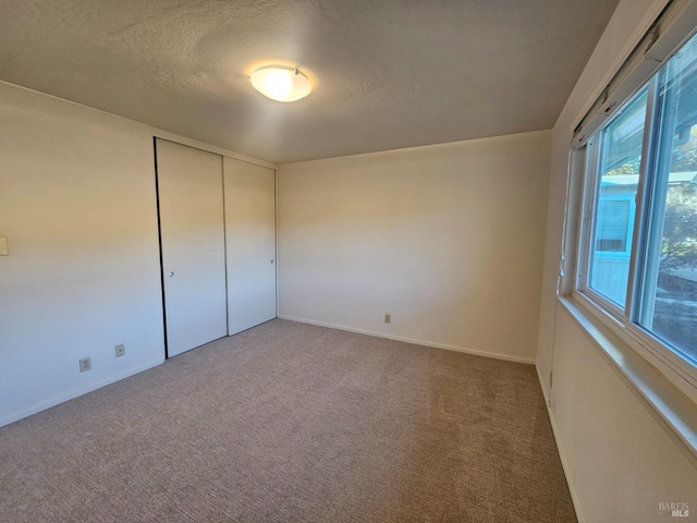 unfurnished bedroom with carpet floors, a textured ceiling, and a closet