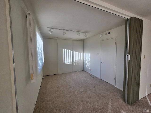 carpeted spare room with track lighting