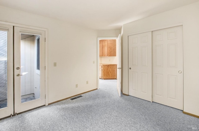 unfurnished bedroom with light carpet and a closet