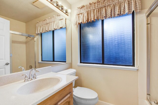 bathroom featuring a wealth of natural light, vanity, and toilet