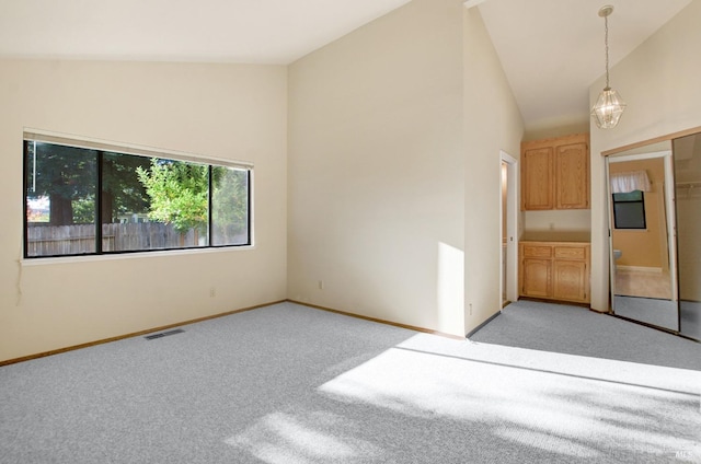 carpeted empty room with high vaulted ceiling