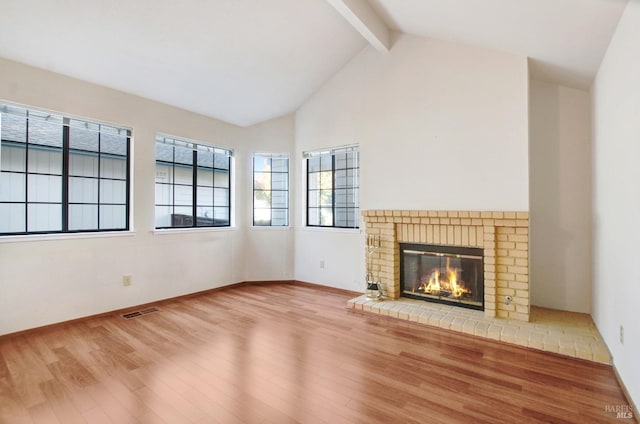 unfurnished living room with beam ceiling, wood-type flooring, a fireplace, and high vaulted ceiling