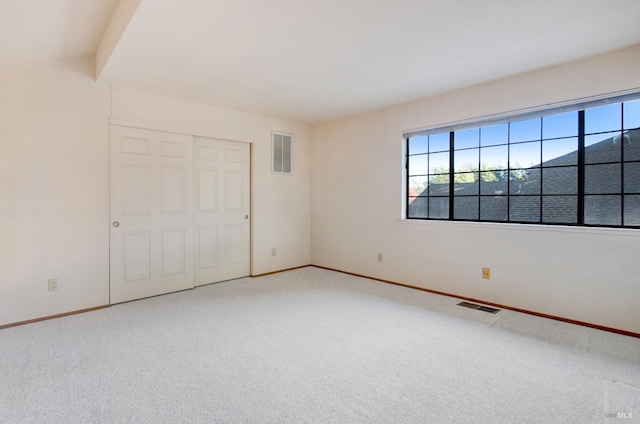 unfurnished bedroom with a closet, carpet floors, and vaulted ceiling