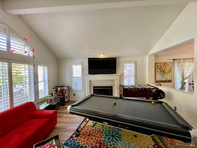 game room featuring a tiled fireplace, pool table, a healthy amount of sunlight, and light hardwood / wood-style floors