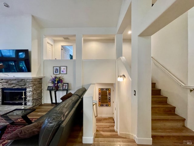 stairway with hardwood / wood-style flooring and a stone fireplace