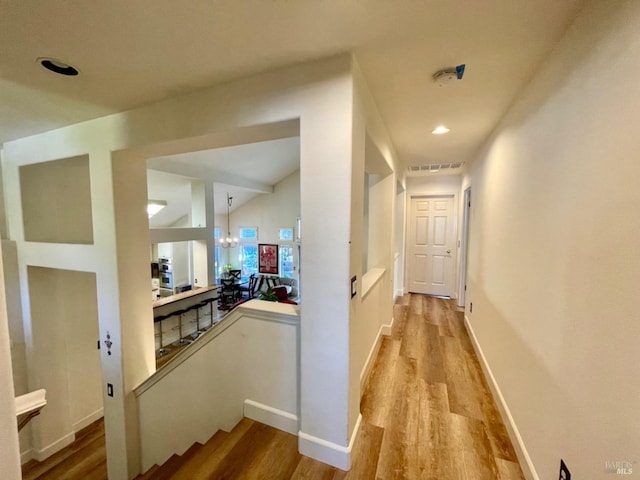 hallway featuring a chandelier and light hardwood / wood-style flooring