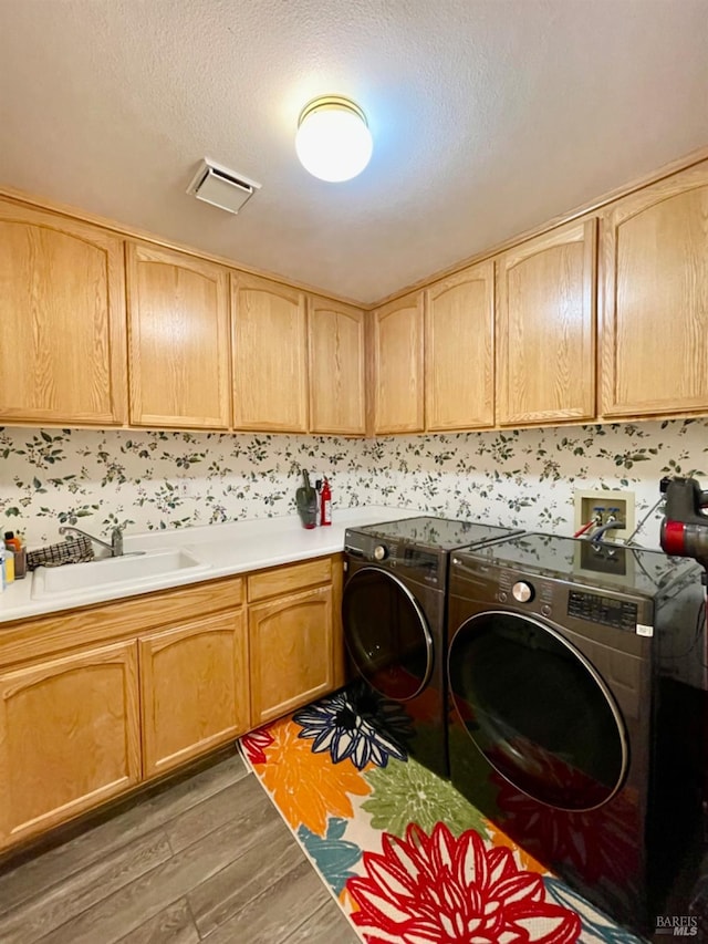 laundry area featuring washing machine and clothes dryer, sink, cabinets, dark hardwood / wood-style flooring, and a textured ceiling