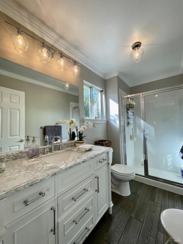 bathroom featuring walk in shower, vanity, crown molding, hardwood / wood-style floors, and toilet