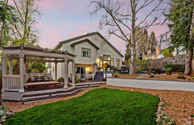 back house at dusk with a lawn, a hot tub, and a deck