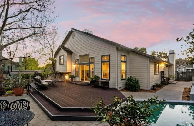 back house at dusk featuring a swimming pool side deck