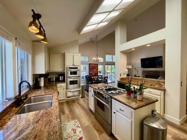 kitchen featuring sink, stainless steel appliances, hanging light fixtures, an inviting chandelier, and light hardwood / wood-style flooring