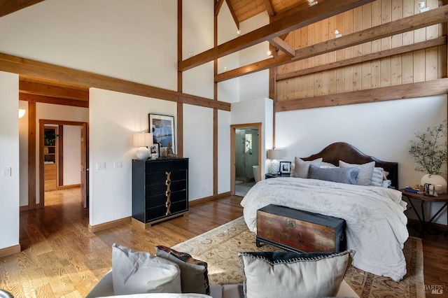 bedroom with beam ceiling, high vaulted ceiling, and light wood-type flooring