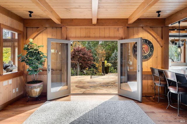 entryway with hardwood / wood-style floors, wood walls, beamed ceiling, and french doors