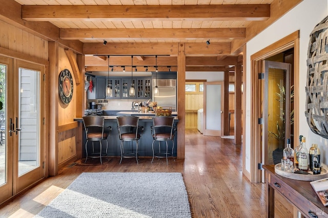 kitchen with wooden walls, dark hardwood / wood-style floors, built in fridge, and a breakfast bar area