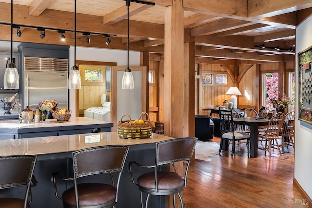 bar with track lighting, decorative light fixtures, built in refrigerator, and washing machine and clothes dryer