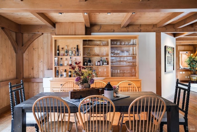 dining room with hardwood / wood-style floors, wood ceiling, beamed ceiling, and wooden walls