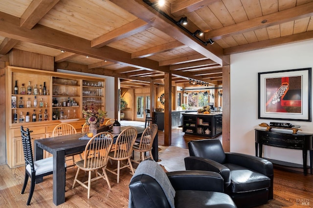 dining room with hardwood / wood-style flooring, wooden ceiling, beamed ceiling, and bar area