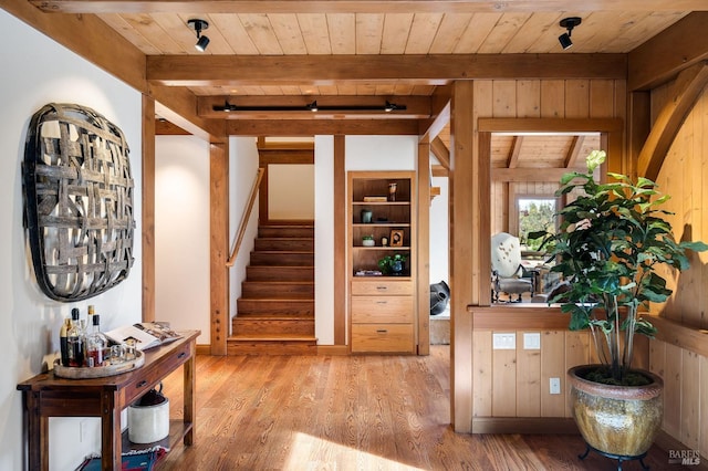 interior space featuring beamed ceiling, light hardwood / wood-style floors, wood walls, and wooden ceiling