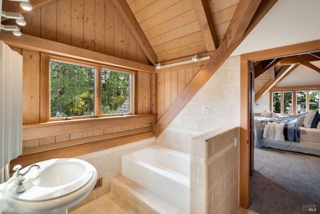 bathroom featuring vaulted ceiling with beams, a bathtub, plenty of natural light, and wood ceiling