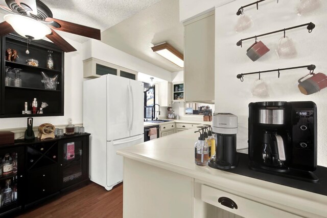 kitchen with sink, dark hardwood / wood-style floors, black dishwasher, white refrigerator, and a textured ceiling