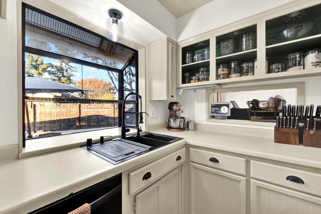 kitchen featuring white cabinetry, black dishwasher, and sink