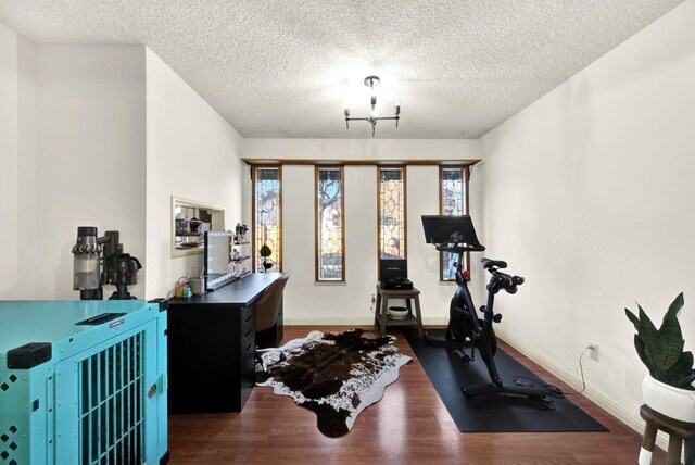 workout area with dark hardwood / wood-style flooring and a textured ceiling