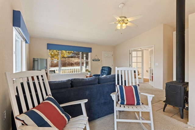 tiled living room featuring a wood stove, ceiling fan, and vaulted ceiling