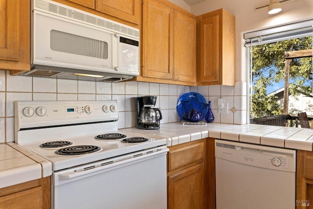 kitchen featuring tile countertops, decorative backsplash, and white appliances