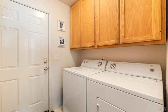 laundry room featuring washer and clothes dryer and cabinets