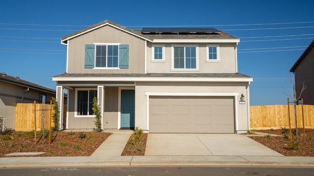 traditional-style home with driveway, an attached garage, fence, and roof mounted solar panels