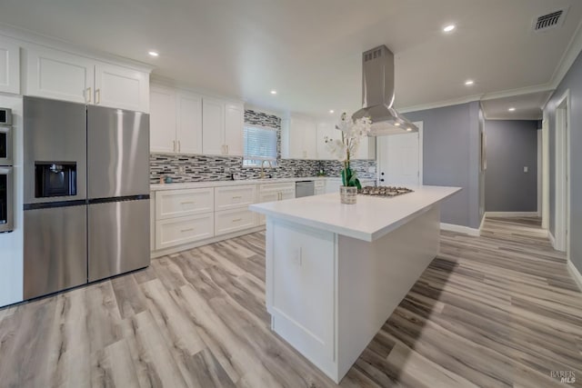 kitchen with crown molding, island exhaust hood, white cabinetry, and stainless steel appliances