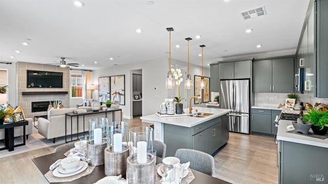 kitchen with tasteful backsplash, gray cabinetry, a kitchen island with sink, and stainless steel appliances