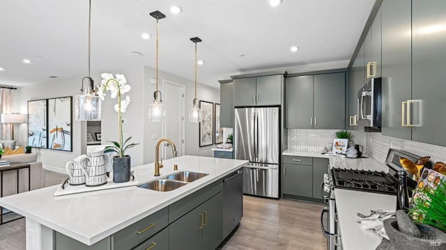 kitchen with backsplash, stainless steel appliances, sink, decorative light fixtures, and gray cabinets