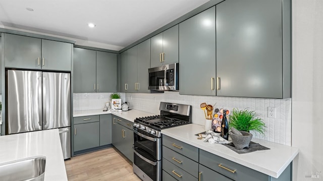 kitchen featuring gray cabinetry, decorative backsplash, stainless steel appliances, and light wood-type flooring