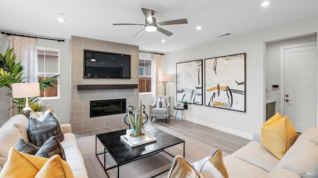 living room with ceiling fan, a fireplace, and light hardwood / wood-style flooring