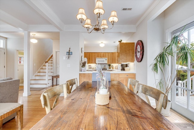 dining area with light hardwood / wood-style floors, ornamental molding, and a chandelier