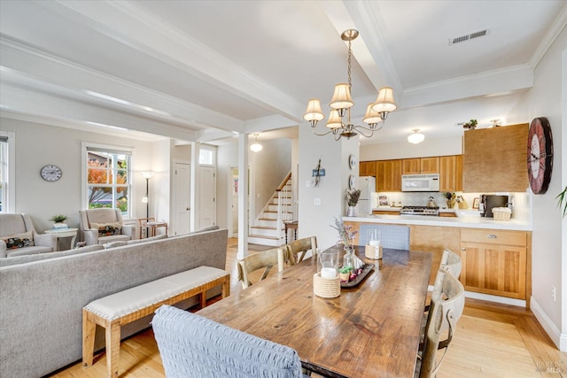 dining area with ornamental molding, a notable chandelier, and light wood-type flooring