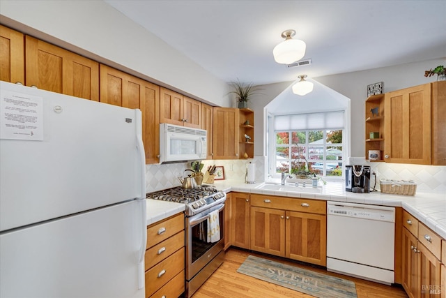 kitchen with white appliances, sink, light hardwood / wood-style flooring, tasteful backsplash, and tile counters