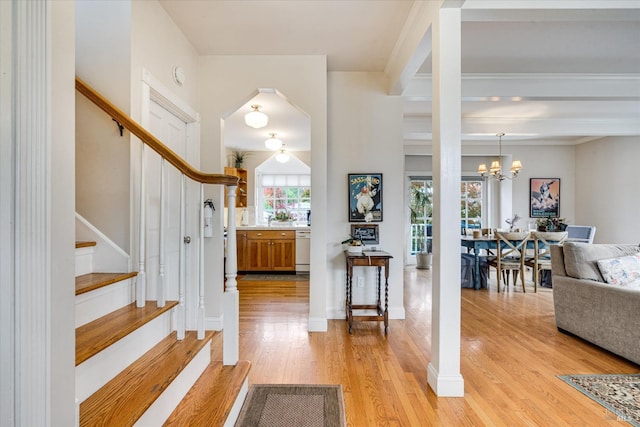 foyer entrance featuring light hardwood / wood-style floors, crown molding, and a chandelier