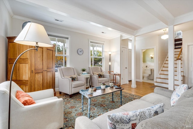 living room with beamed ceiling, light hardwood / wood-style floors, and crown molding