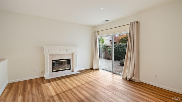 unfurnished living room featuring light wood-style flooring, baseboards, and a tiled fireplace