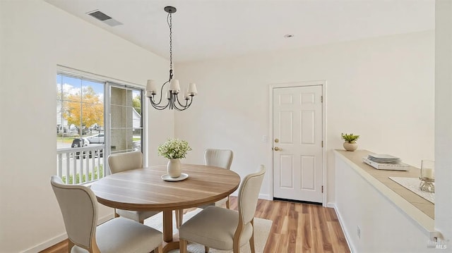 dining area featuring visible vents, light wood-style flooring, baseboards, and an inviting chandelier