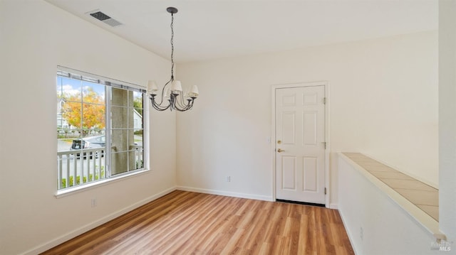 unfurnished dining area with a notable chandelier, light wood finished floors, visible vents, and a healthy amount of sunlight