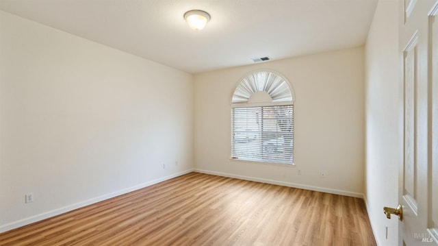 spare room with baseboards, visible vents, and light wood-style floors