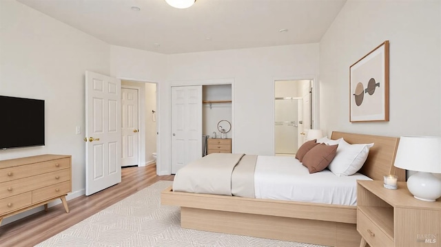 bedroom featuring ensuite bath, a closet, wood finished floors, and baseboards