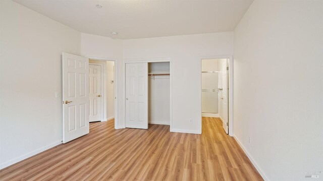 unfurnished bedroom with light hardwood / wood-style floors and a closet